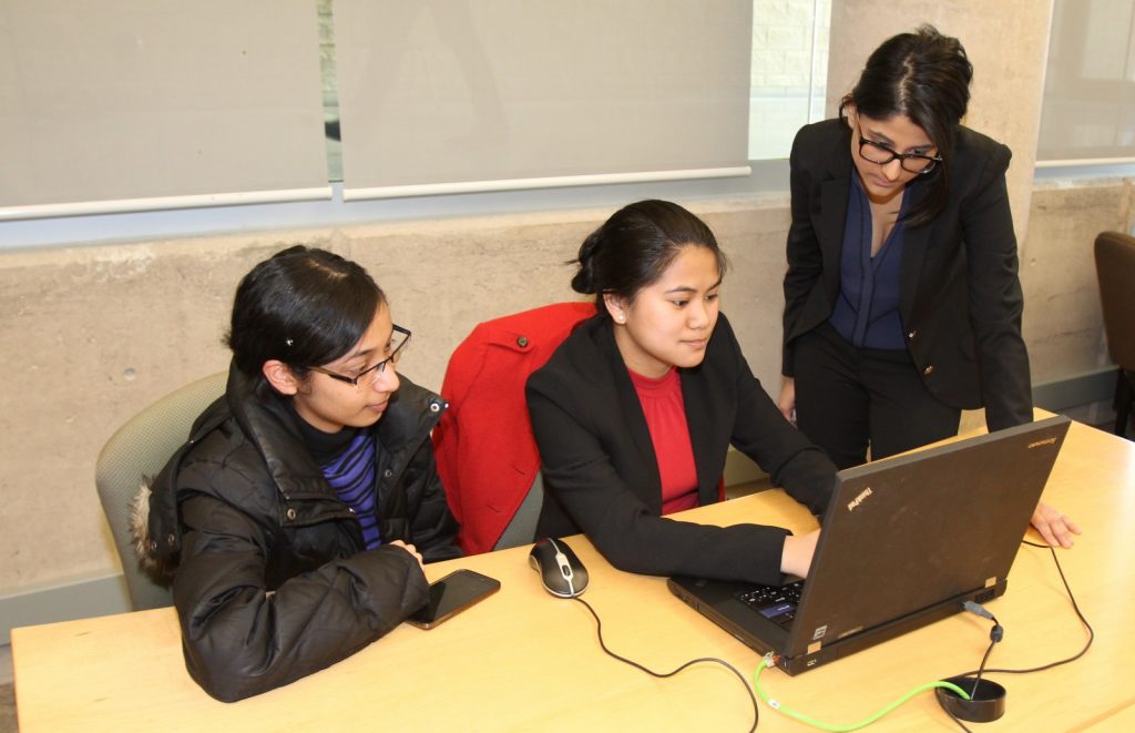 Student Feby Jose, left, gets tax preparation help from Accounting Co-Op students Alyssa Gambel and Shreya Verma.
